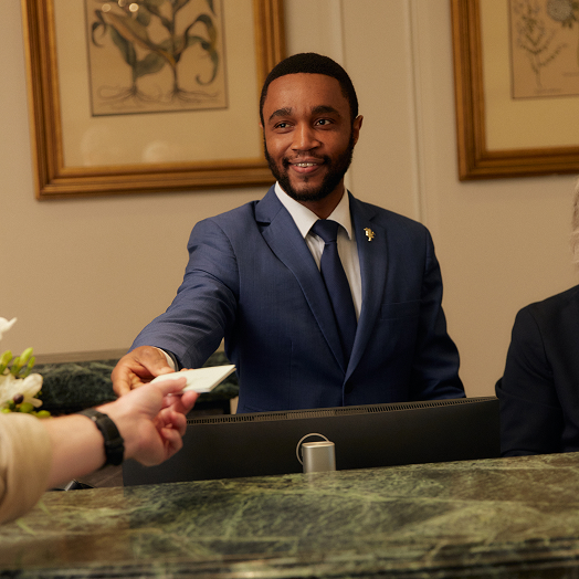 This image depicts a man working at the hotel handing a key card to a guest