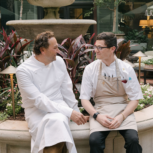 This image depicts two Chef's sitting outside by a fountain