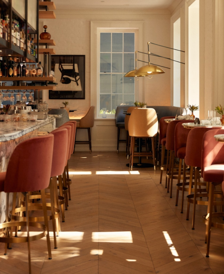 Stylish restaurant interior with a bar and surrounding table seating in a contemporary setting.