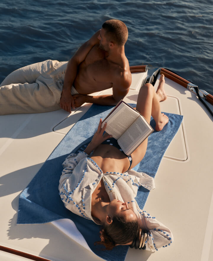 Couple on a boat in the ocean at The Cooper, reading a book and relaxing together.