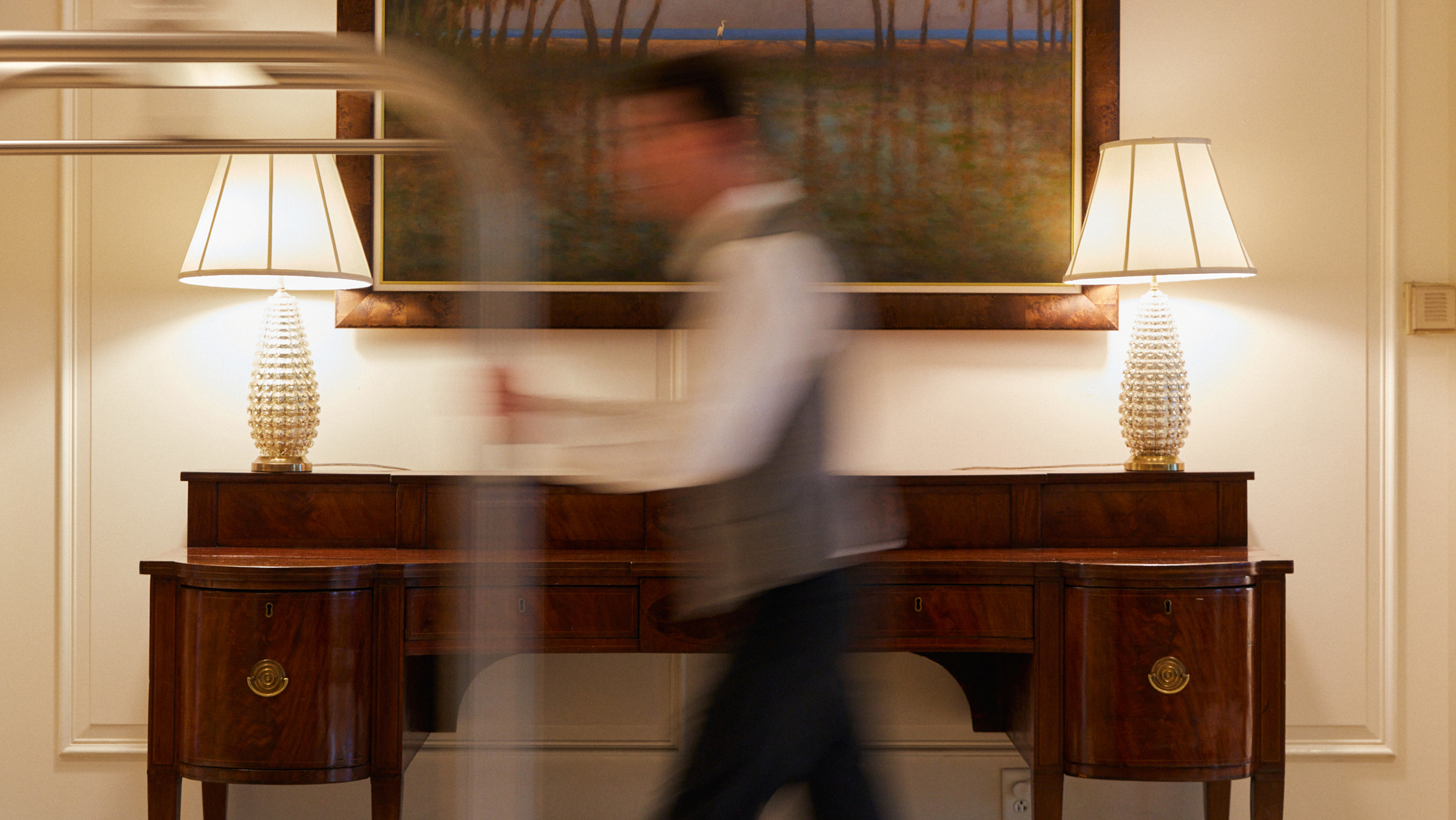 This image depicts a bell man at the hotel walking with a luggage cart