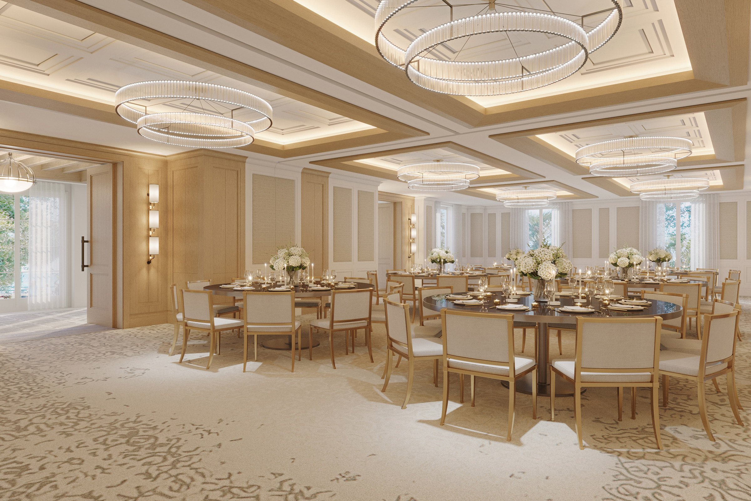 A grand ballroom gathering area with tables and chairs with luxurious carpet, lighting, and tan accents.
