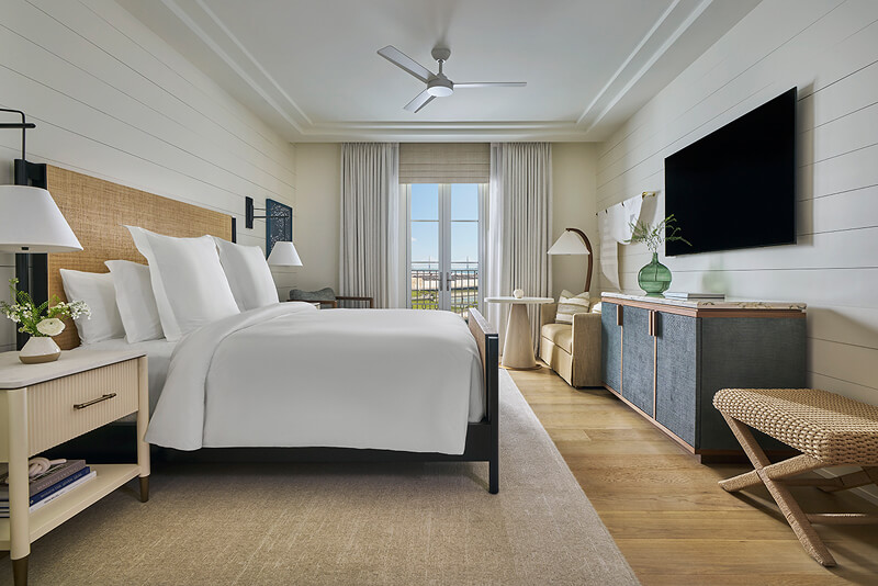 this image depicts a hotel bedroom with a freshly made bed