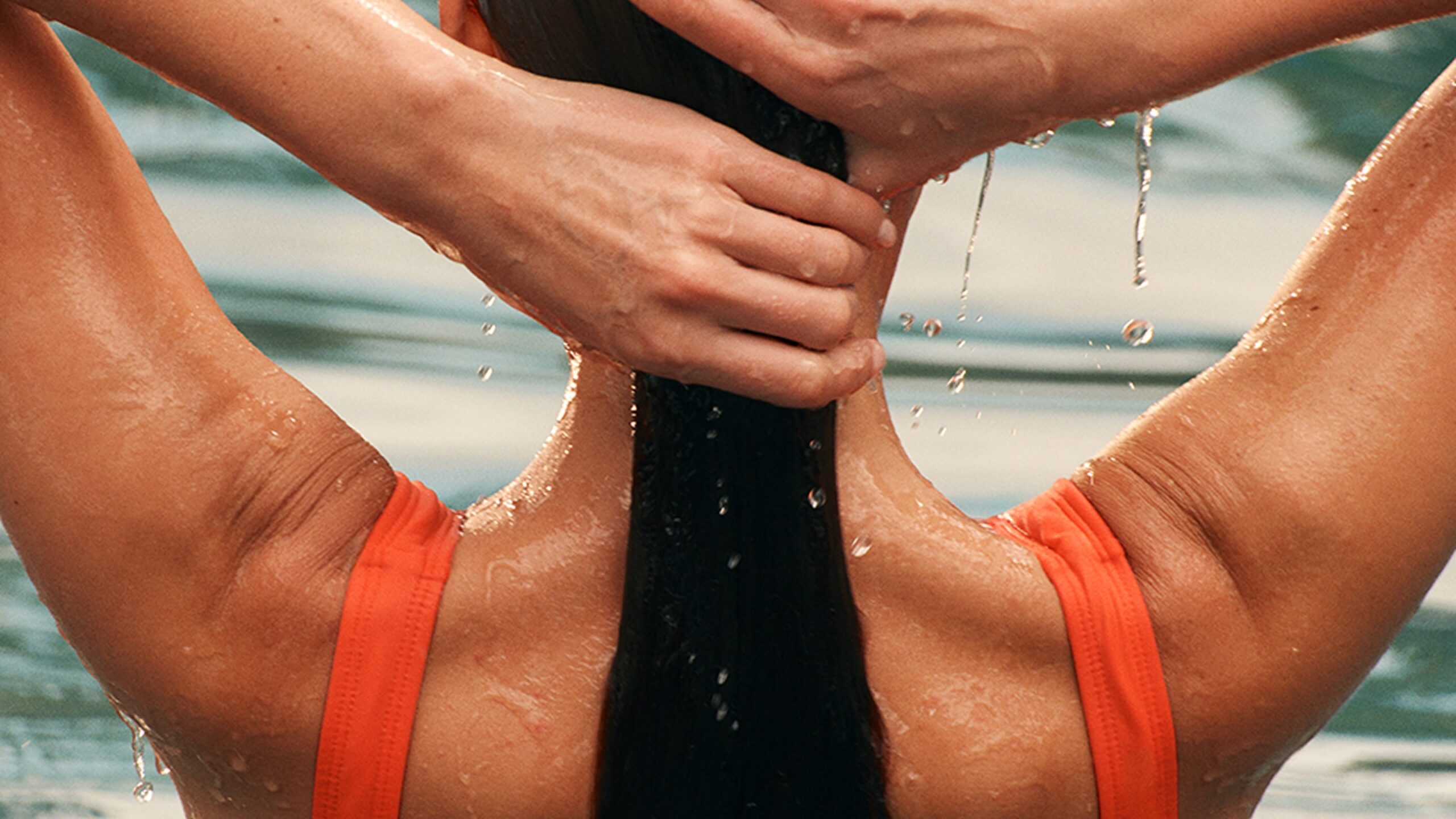 this image depicts a woman in a pool with an orange bathingsuit
