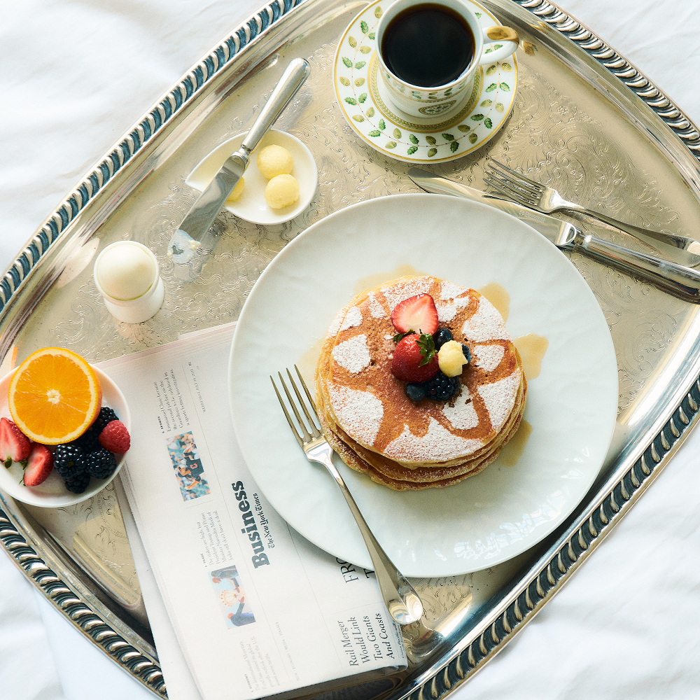 This image depicts a plate of pancakes and berries on a tray for room service