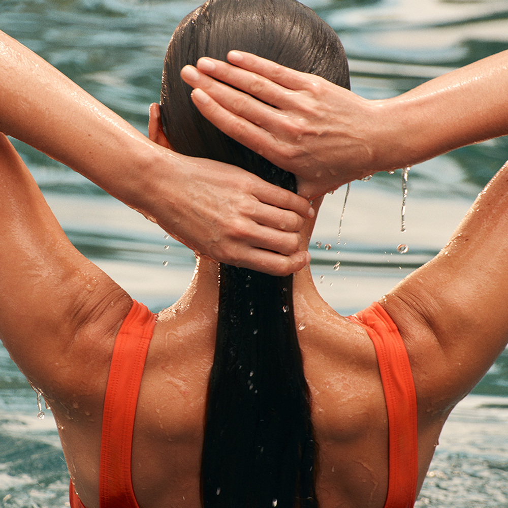 This image depicts a woman in the water with an orange bathing suit