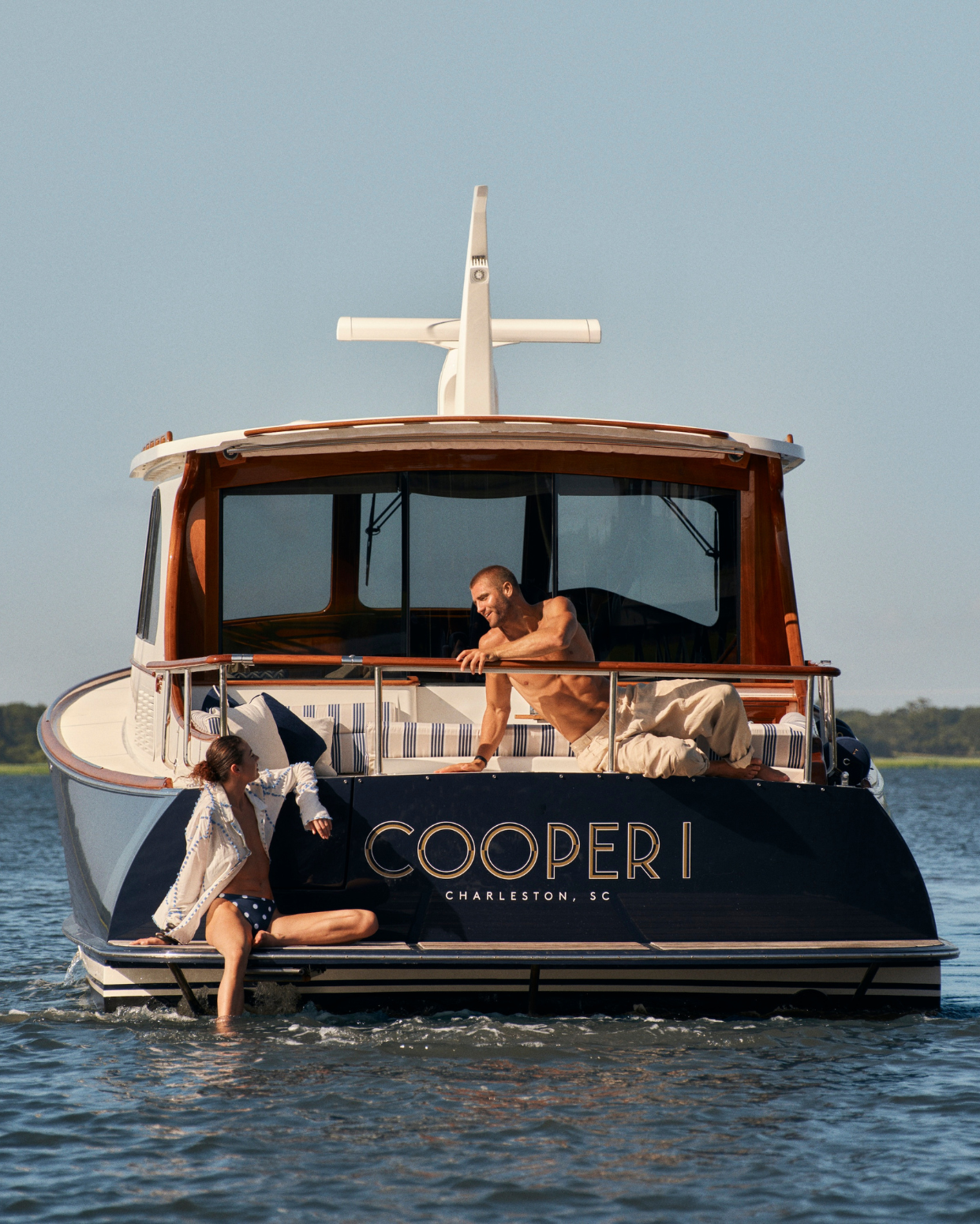 Image of two people on the back of a Hinckley boat enjoying the water.
